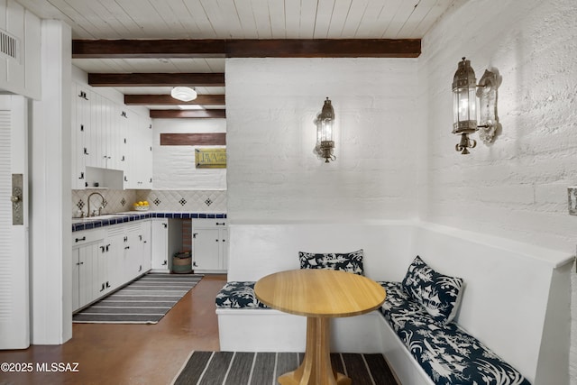 kitchen featuring beamed ceiling, white cabinetry, sink, decorative backsplash, and wood ceiling