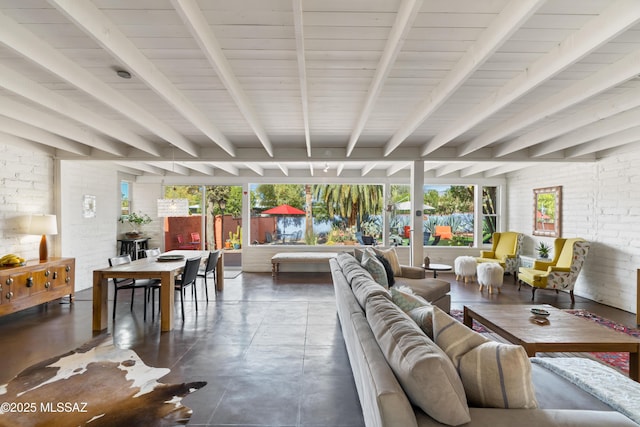 living room featuring beamed ceiling, brick wall, and a wealth of natural light