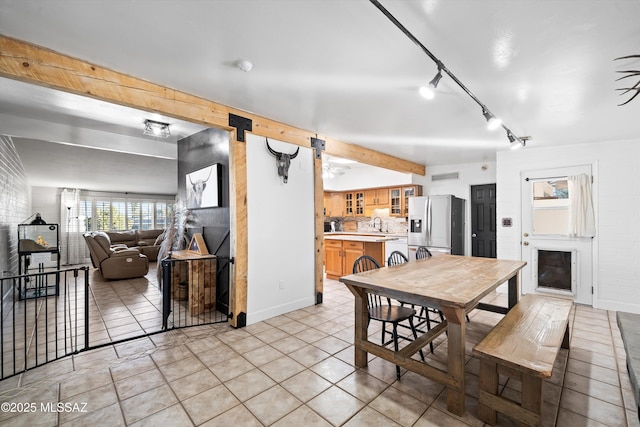 tiled dining space with beam ceiling, a fireplace, and sink