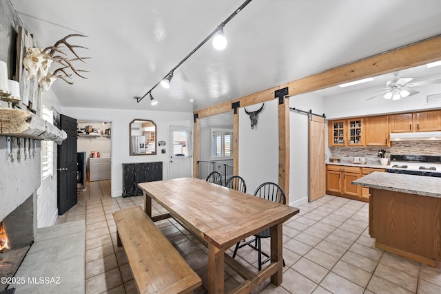 tiled dining space with ceiling fan, a barn door, and washer / clothes dryer