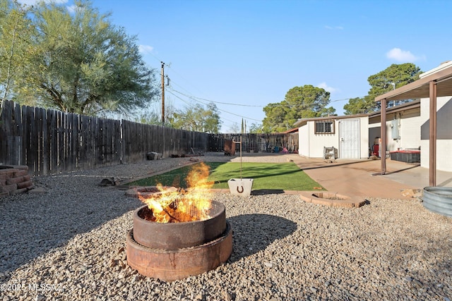 view of yard featuring a fire pit, an outdoor structure, and a patio