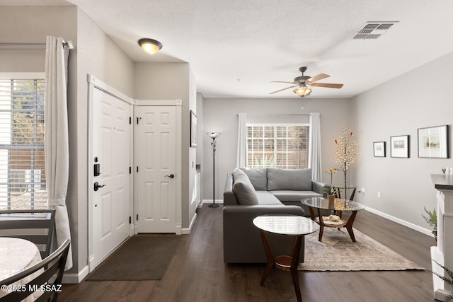 living room with ceiling fan, dark hardwood / wood-style floors, and a textured ceiling