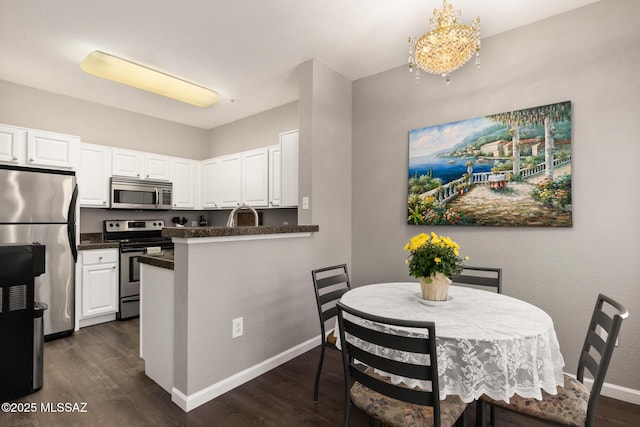 kitchen with decorative light fixtures, white cabinetry, dark hardwood / wood-style floors, and stainless steel appliances