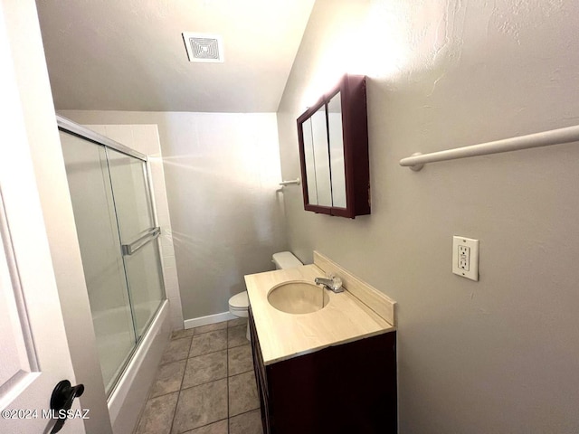 full bathroom featuring toilet, vaulted ceiling, tile patterned flooring, shower / bath combination with glass door, and vanity