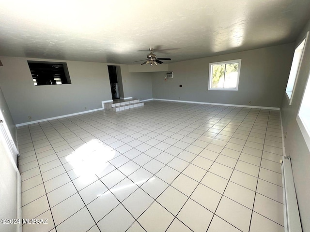 unfurnished living room with a wall mounted AC, ceiling fan, and light tile patterned flooring