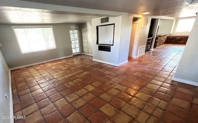 tiled empty room with a textured ceiling