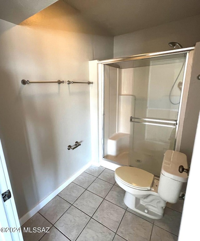 bathroom with toilet, a shower with door, and tile patterned floors