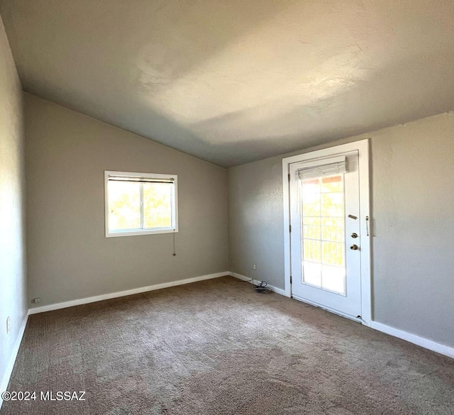 carpeted spare room featuring vaulted ceiling