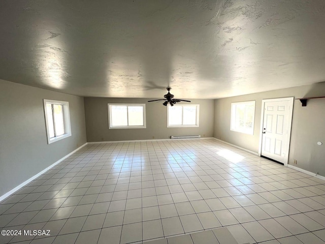 tiled spare room with baseboard heating and ceiling fan