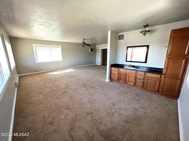 unfurnished living room with ceiling fan, light carpet, and a textured ceiling