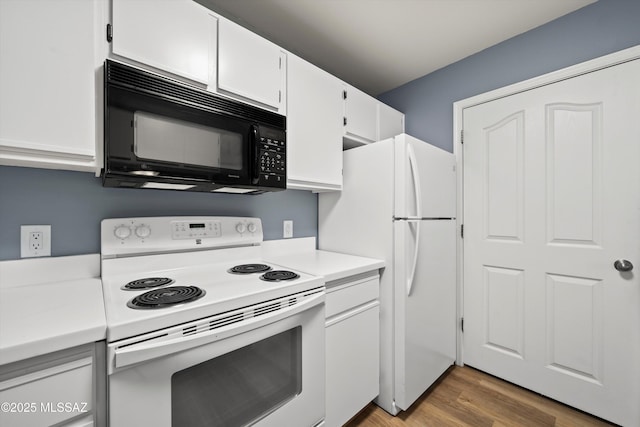 kitchen with white appliances, white cabinetry, and hardwood / wood-style floors