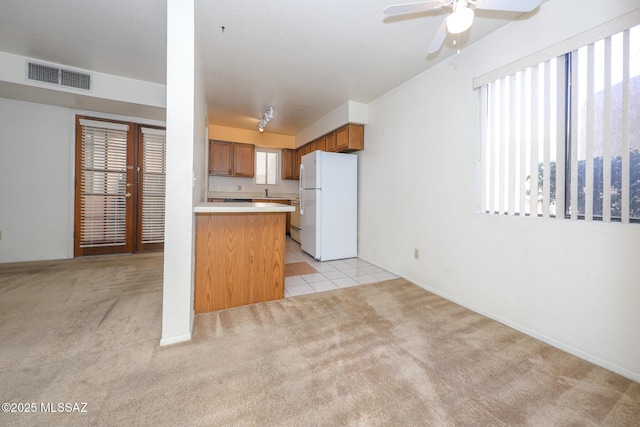 kitchen featuring french doors, light colored carpet, kitchen peninsula, and white fridge