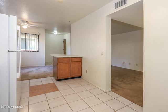 kitchen featuring white refrigerator, light colored carpet, ceiling fan, and kitchen peninsula