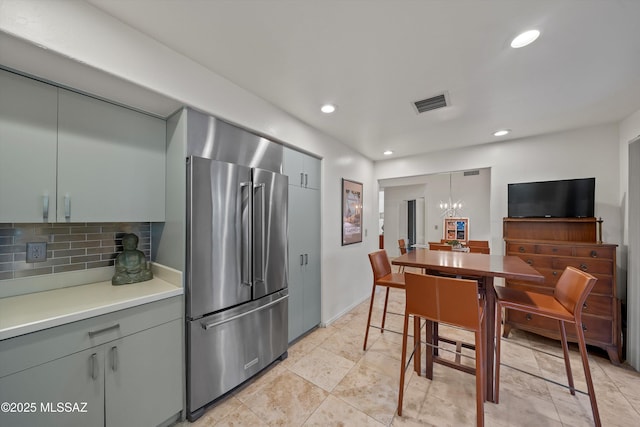 kitchen featuring a notable chandelier, backsplash, hanging light fixtures, and high quality fridge