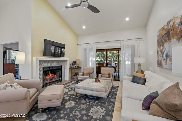 living room with ceiling fan, a tile fireplace, and high vaulted ceiling