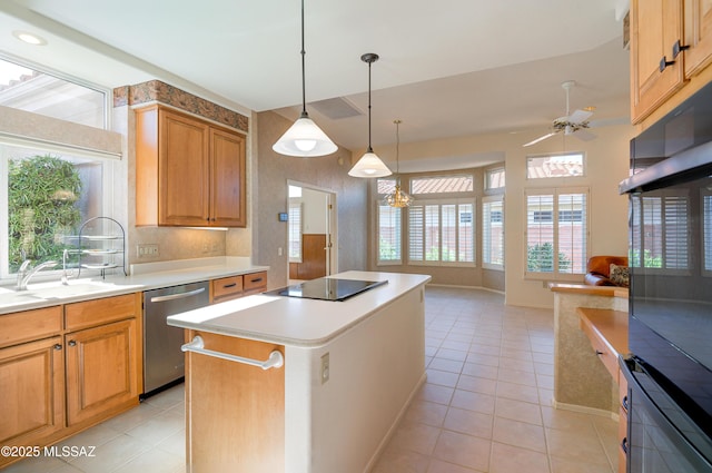 kitchen featuring pendant lighting, a center island, black appliances, sink, and light tile patterned floors