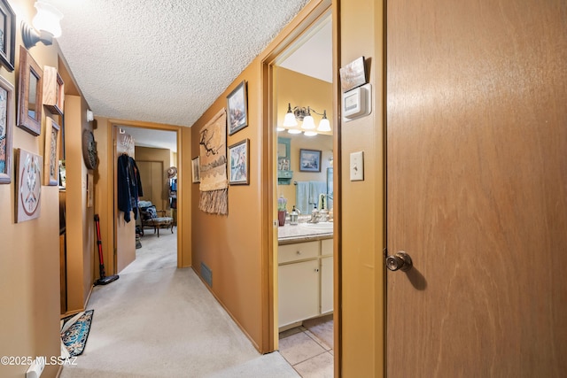 hallway with a textured ceiling and light colored carpet