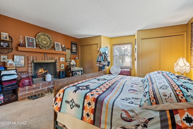 bedroom featuring a fireplace, a textured ceiling, carpet, and multiple closets