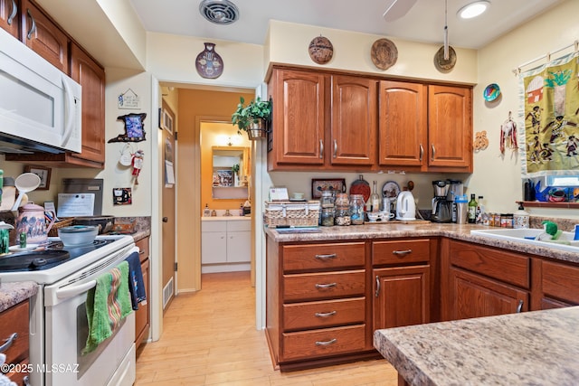 kitchen with white appliances, light hardwood / wood-style floors, and sink