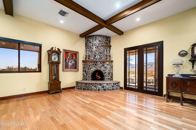 living room with french doors, a fireplace, beam ceiling, and light hardwood / wood-style flooring