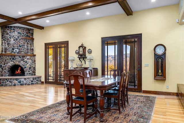 dining room with beamed ceiling, a fireplace, french doors, and light wood-type flooring