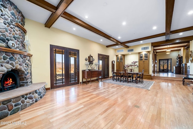 living room with french doors, coffered ceiling, beam ceiling, light wood-type flooring, and a fireplace