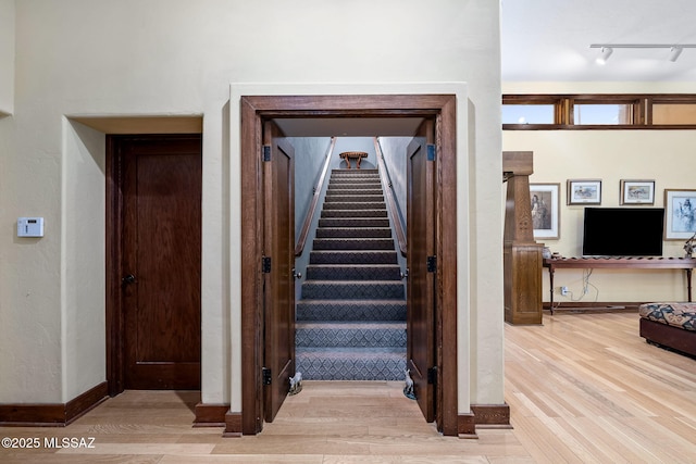 staircase with hardwood / wood-style flooring, track lighting, and a high ceiling