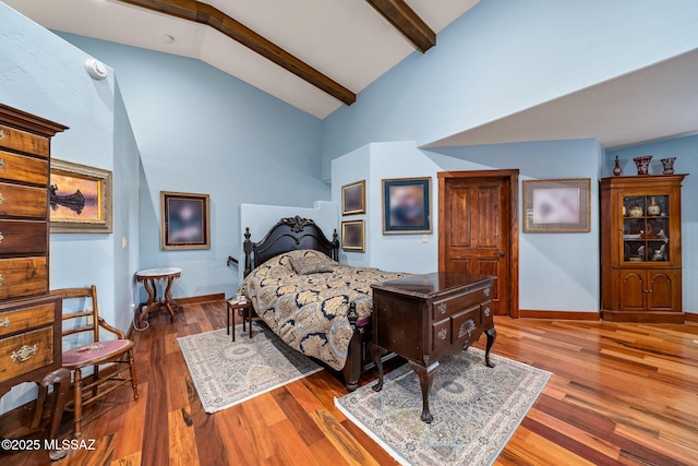 bedroom featuring hardwood / wood-style flooring, beam ceiling, and high vaulted ceiling