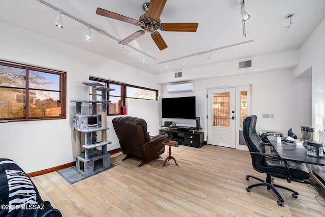 office space featuring ceiling fan, a wealth of natural light, a wall unit AC, and light hardwood / wood-style flooring