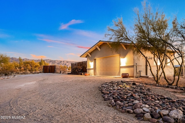 property exterior at dusk featuring a garage and a mountain view