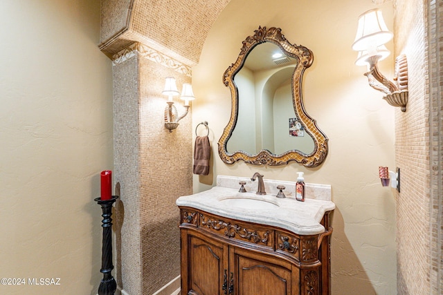 bathroom featuring brick ceiling, lofted ceiling, and vanity