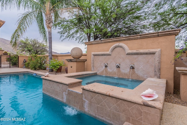 view of swimming pool with pool water feature and an in ground hot tub