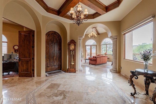 foyer featuring ornate columns, a high ceiling, an inviting chandelier, and ornamental molding