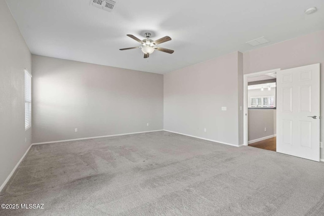 spare room with ceiling fan and dark colored carpet