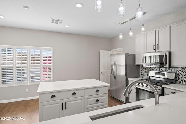 kitchen with stainless steel appliances, sink, white cabinets, decorative light fixtures, and backsplash