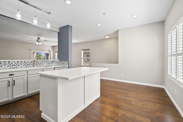 kitchen featuring a kitchen island, ceiling fan, decorative light fixtures, and dark hardwood / wood-style floors