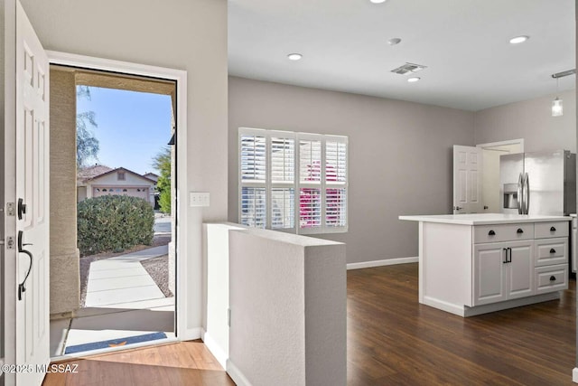 kitchen featuring dark hardwood / wood-style flooring, white cabinetry, kitchen peninsula, and stainless steel refrigerator with ice dispenser