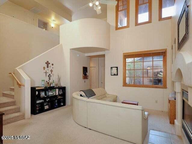 living room featuring a high ceiling, light carpet, and ceiling fan