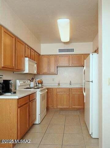 kitchen with white appliances, sink, and light tile patterned floors