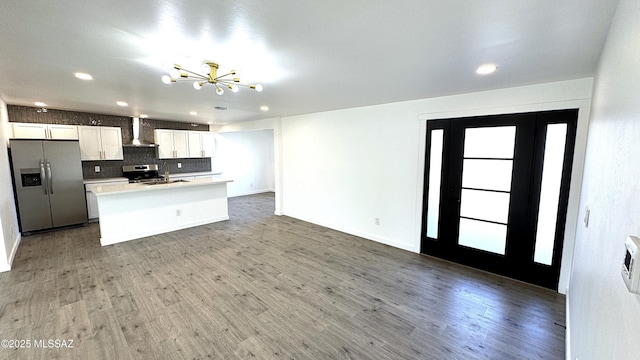 kitchen featuring appliances with stainless steel finishes, an island with sink, wall chimney exhaust hood, white cabinets, and sink