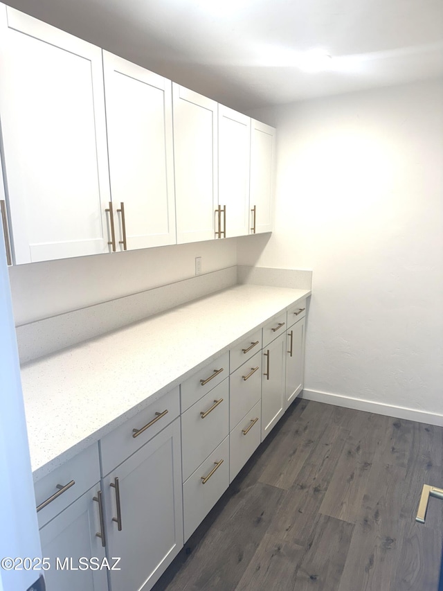 bar with light stone countertops, dark hardwood / wood-style flooring, and white cabinetry