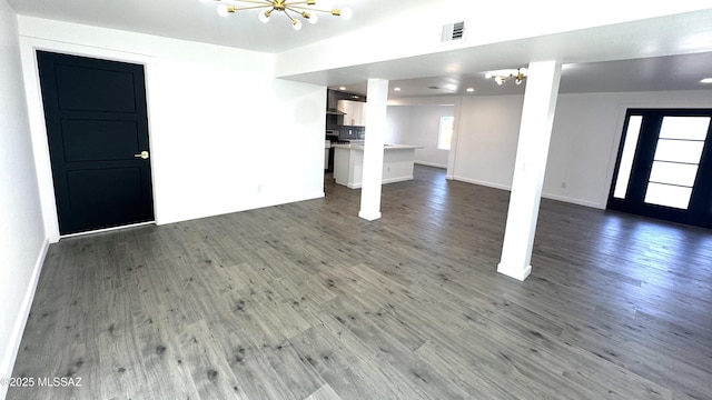 unfurnished living room with an inviting chandelier and dark hardwood / wood-style floors