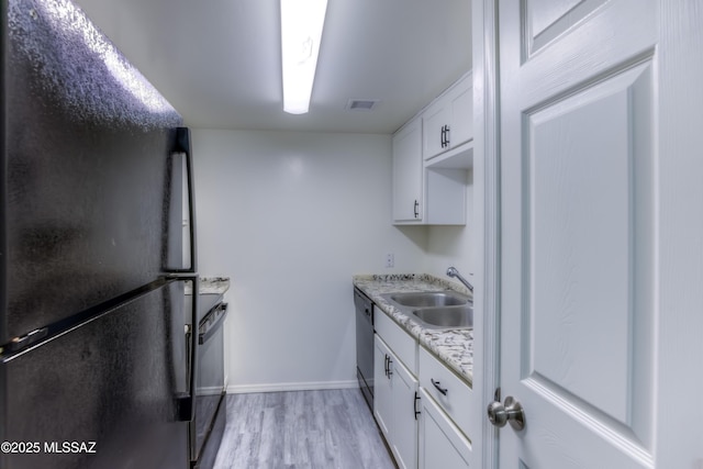 kitchen featuring light stone countertops, white cabinets, black appliances, sink, and light hardwood / wood-style flooring