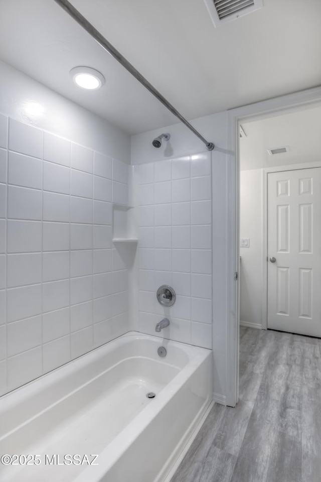 bathroom with tiled shower / bath combo and wood-type flooring