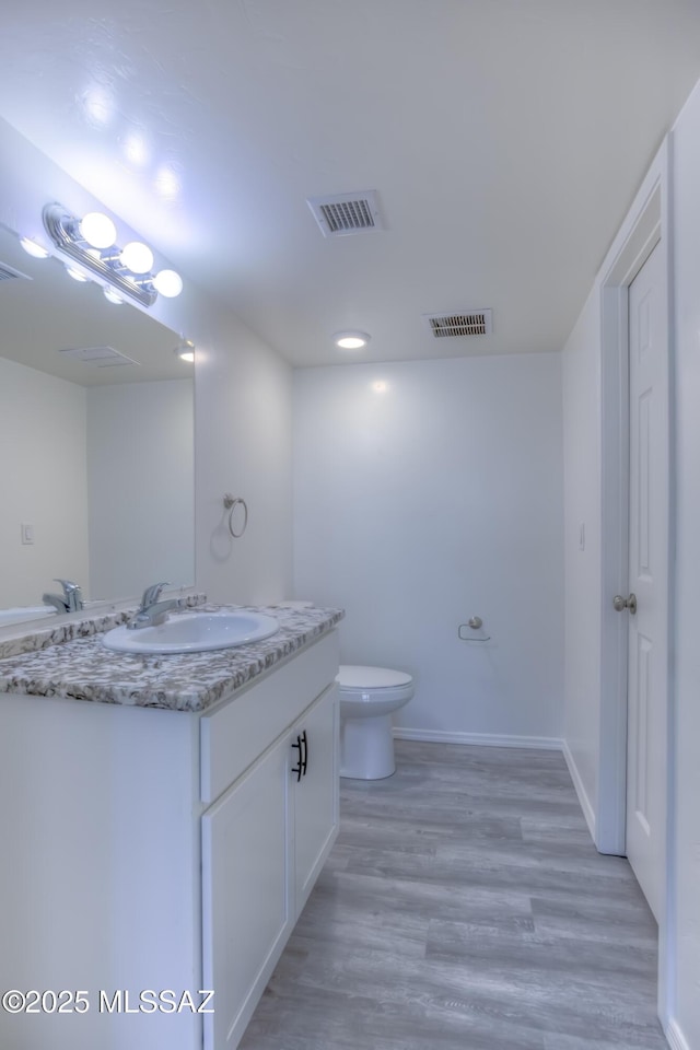 bathroom with hardwood / wood-style floors, toilet, and vanity