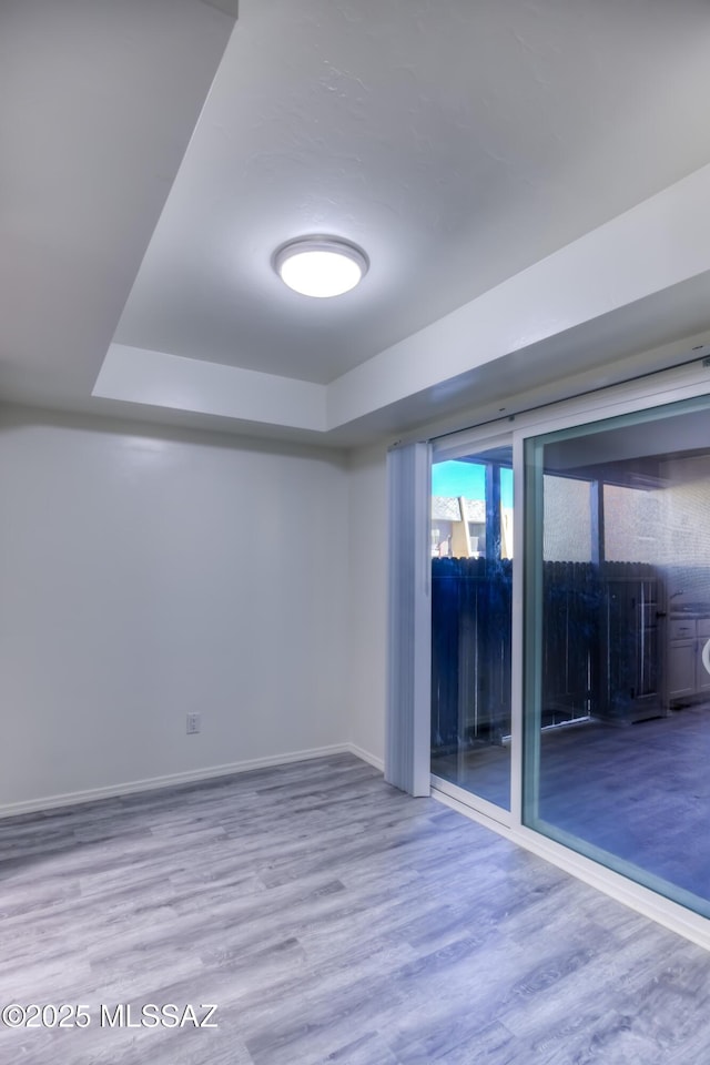 empty room with hardwood / wood-style floors and a raised ceiling