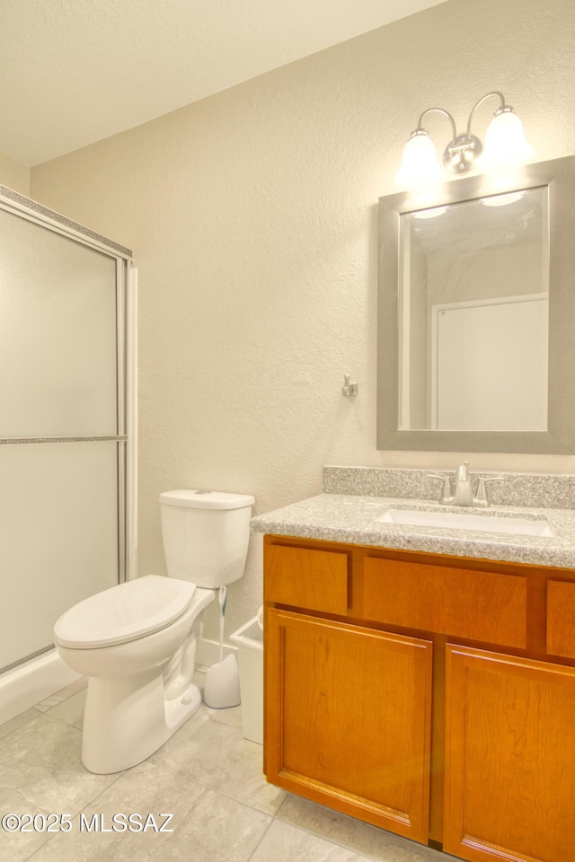 bathroom with a shower with door, toilet, vanity, and tile patterned flooring