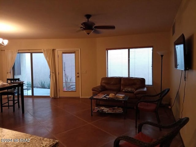 tiled living room with plenty of natural light and ceiling fan with notable chandelier