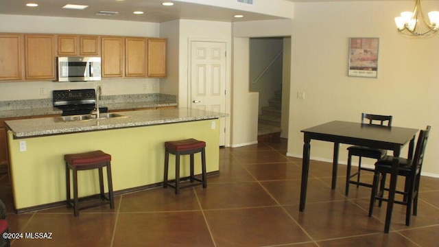 kitchen with hanging light fixtures, an island with sink, a breakfast bar, dark tile patterned flooring, and sink