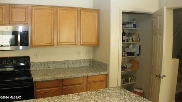 kitchen with black electric range and light stone countertops